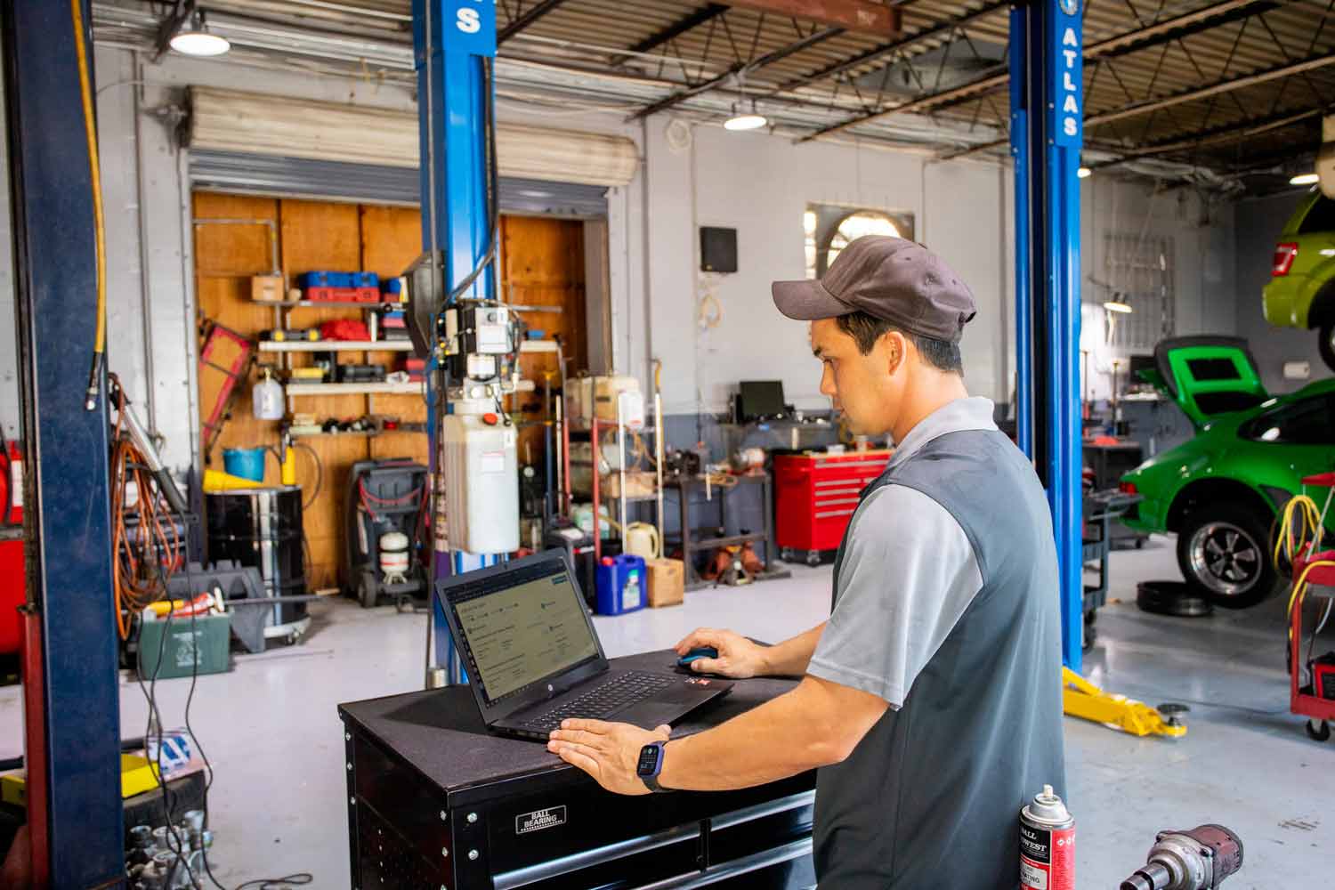 man working at computer inside auto repair shop